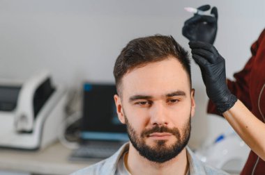 Saç dökülmesi tedavisi için kafa derisi enjeksiyonu alan hasta, bir erkek saç uzmanı kozmetik ameliyatı yapıyor.