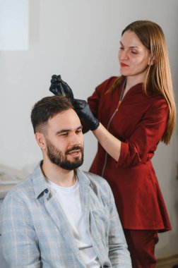 Saç dökülmesini gidermek için profesyonel bir kafa bakımı prosedürü ve mezoterapi seansı geçiren bir erkek hasta