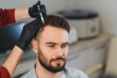 Trikoloji kliniğinde saç büyütme uyarısı için kafa derisine mezoterapi yapılan bir hasta.