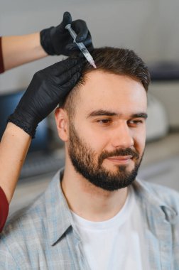 Bir adamın kafa derisine mezoterapi enjeksiyonu yapan, saç büyümesini teşvik eden ve saç dökülmesini ele alan profesyonel bir trikoloğum.