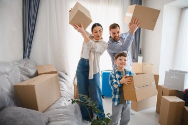 Aileler ve çocuklar yeni dairelerine karton kutular taşıyarak heyecan verici yerlerinin keyfini çıkarıyorlar. Mutluluk ve başarıyı hissediyorlar.