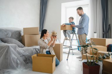 Mutlu aile oturma odasındaki eşyaları boşaltıyor, yeni dairenin taşınmasını kutluyor ve oyuncak gemi gibi eşyaları keşfediyor.