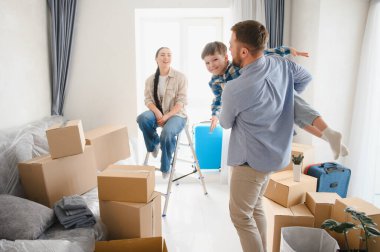 Aile yeni bir evde kutuları topluyor ve gülümsüyor. Baba oğluyla oynarken anne izliyor, taşınmayı kutluyor.