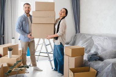 Taşınan kutuları taşıyan genç bir çift, yeni dairelerinde mutlu ve heyecanlı hissediyorlar. Yer değiştirme ve başlama kavramı