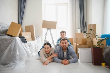 Aileler ve çocuklar taşınma günü karton kutuların arasında yeni evlerinin keyfini çıkarıyorlar. Taşınmak için mutlu ve heyecanlılar.