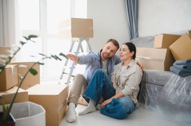 Genç çift gelecek planlarını tartışıyor, yeni apartman planlarını hayal ederken etrafları kutu ve mobilyalarla çevrili.