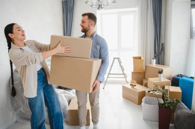 Karton kutular taşıyan genç bir çift yeni evlerine taşınıyorlar. Gayrimenkul, konut ve mutlu yaşam tarzı kavramı