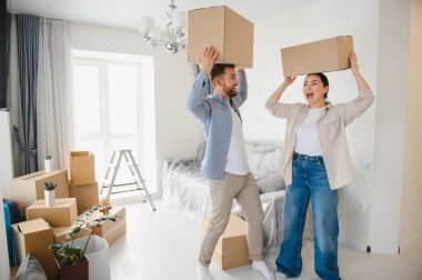 Kafalarında karton kutular taşıyan neşeli genç çift yeni bir ev ve yeni bir başlangıç kutluyor.