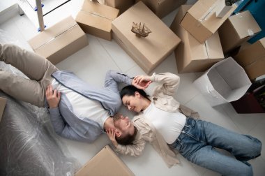 Mutlu çift, yeni evlerine taşındıktan sonra kutuları boşaltmak için dairenin zemininde dinleniyor.