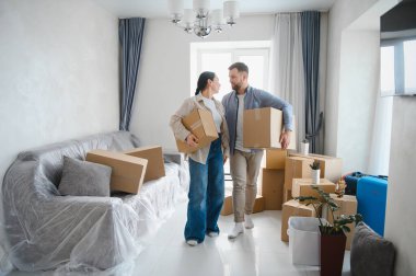 Karton kutular taşıyan mutlu çift yeni oturma odalarında bavullarını boşaltmaya hazırlanıyor. Yeniden yerleştirme konsepti