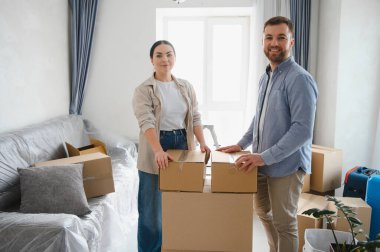 Yeni evlerinde birlikte duran mutlu genç çift kutuları taşıyarak yeni bir hayata başlıyorlar.