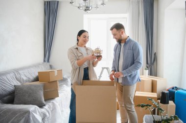 Yeni oturma odalarında kutuları boşaltan mutlu bir çift. Taşınmayı ve yeni bir başlangıç yapmayı kutluyorlar.