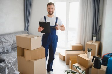 Dostane, profesyonel bir nakliyeci elinde bir pano, yeni bir dairede kutuları taşırken başparmağını kaldırıyor.