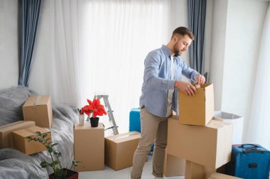 Genç adam karton kutulardan eşyalarını boşaltıp yeni bir daireye yerleşiyor. Yaşam tarzı taşınma konsepti