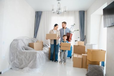 Ebeveynler karton kutular taşıyorlar, mobilyalar örtülü, yeni bir başlangıç ve yeni bir eve taşınmayı kutluyorlar.