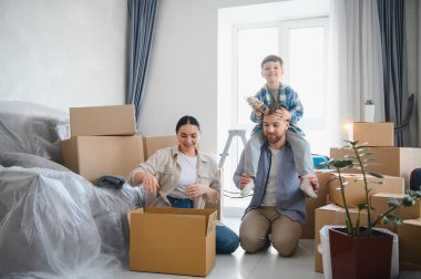 Aile yeni bir dairede karton kutuları açıyor, ebeveynler ve çocuklar taşınma işleminden zevk alıyor, birlikte bir ev yaratıyorlar.