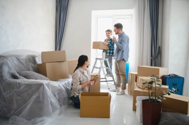 Aile eşyaları karton kutulara konulacak ve taşınma için düzenlenecek. Ebeveynler ve çocuklar yeni bir eve taşınıyor.