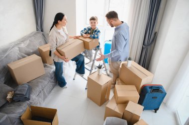 Mutlu bir ailenin yeni bir daireye taşınması, bir çocukla birlikte karton kutuları açması. Gayrimenkul ve mülkiyet kavramı