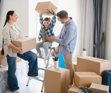 Genç aile taşınmayı kutluyor, modern evlerinde karton kutularla birlikte vakit geçiriyorlar.