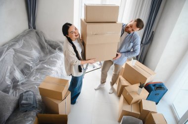 Genç çift karton kutular taşıyor, gülümsüyor ve yeni evlerine taşınıyorlar. İnsanlar taşınma gününün tadını çıkarıyor