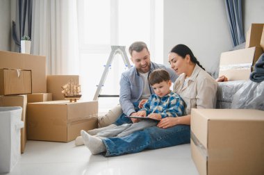 Genç bir aile, anne, baba ve oğul, yeni bir evde oturuyorlar. Etrafı karton kutularla çevrili, taşınmaktan zevk alıyorlar.