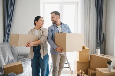 Genç, gülümseyen bir çift yeni bir daireye taşınıyorlar. İnsanlar yeni başlangıçlarda mutluluğu ve aşkı hisseder.