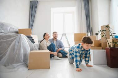 Genç bir aile taşınıyor. Yeni bir dairede oturuyor. Etrafı karton kutularla çevrili.