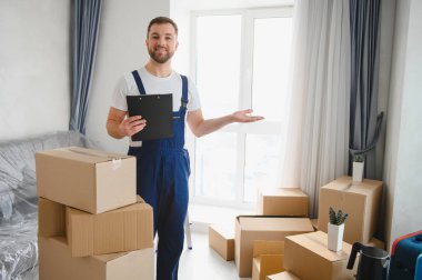 Bir apartmanda kutuları taşıyan, nakliye ve dağıtım hizmeti veren profesyonel bir nakliyeci.