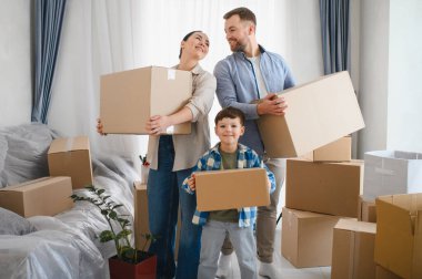 Mutlu aile kutuları taşıyor, yeni evlerine taşınıyorlar, bavullarını açmaya ve yeni bir başlangıç yapmaya hazırlar.