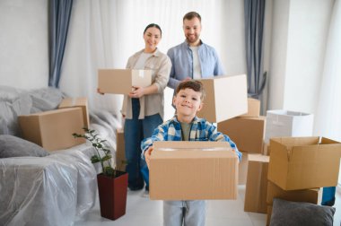 Aile karton kutular taşıyor, yeni evlerine taşınıyor ve birlikte mutlu bir hayata başlıyorlar. Oğul bir paket tutuyor.