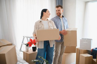 Mutlu çift gülümsüyor ve karton kutular taşıyor, yeni evlerinde ya da dairelerinde birlikte yeni başlangıçları kutluyorlar.