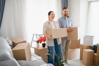 Gülen çift ellerinde karton kutular, yeni evlerine taşınmalarını kutluyorlar, iyimserlikle yeni bir başlangıç yapıyorlar.