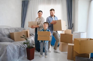 Mutlu aile yeni bir evde eşyalarını boşaltıyor. Ebeveynler ve çocuklar kutu taşıyorlar, taşınıyorlar ve ev yapıyorlar.