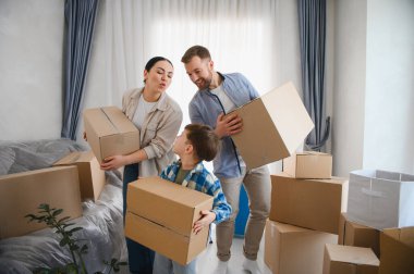 Karton kutular taşıyan çocuklu bir aile yeni bir daireye taşınıyor. Gülümsüyorlar, büyük hareketle mutlu hissediyorlar.
