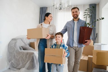Mutlu bir aile yeni bir daireye taşınıyor, kutuları taşıyor, yeni bir evde yeni bir başlangıç yapmayı bekliyor.