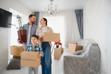 Aile taşınan kutularla yeni eve giriyor. Ebeveynler ve çocuklar hayatlarında yeni bir sayfa açtıkları için mutlular.