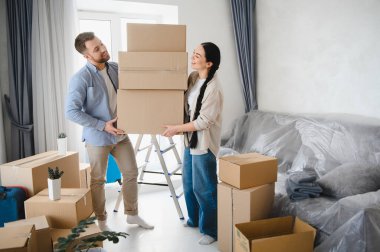 Karton kutuları taşıyan genç bir çift yeni evlerine taşınıyorlar. Yeni bir başlangıç ve ortak bir yolculuğu simgeliyorlar.