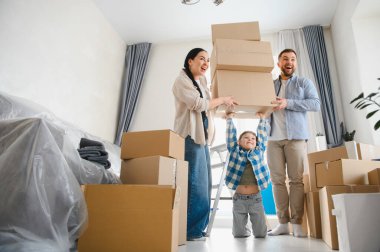 Mutlu bir aile yeni bir daireye taşınıyor, aileler ve çocuklar kutuları taşıyor, taşınma konusunda heyecanlılar.