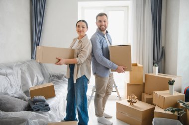 Mutlu çift sırt sırta durarak, yeni dairelerinde karton kutular taşıyorlar, taşınmaya ve yeni bir başlangıç yapmaya hazırlar.