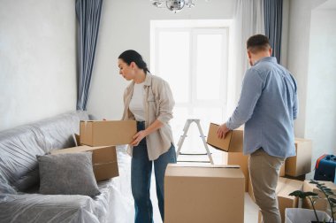 Genç çift yeni bir bölüme başlıyor, yeni dairelerine karton kutular taşıyorlar. Paketlerin açılması ve ev kurulumu için hazırlanılıyor