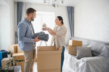Kutuları açarken gülümseyen ve dekorasyon düzenleyen genç çift, yeni modern evlerine yerleşiyorlar ve birlikte yeni bir başlangıç yapıyorlar.