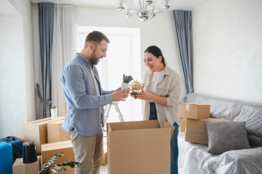 Çift gülerken yeni evlerindeki karton kutuların süslemelerini açıyorlar. Birlikte yeni bir hayata başlıyorlar.