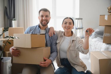 Genç çift yeni bir daireye taşınmayı kutluyorlar. Evin anahtarlarını ve karton kutuları tutuyorlar. Birlikte yeni bir hayata başlamak.