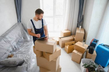 Profesyonel nakliyeci, yeni bir dairede karton kutular ve bavullarla çevrili, taşınmaya hazırlanıyor.