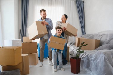Mutlu bir aile yeni bir daireye taşınıyor, kutuları birlikte taşıyorlar. Taşınırken ebeveynler ve çocuklar gülümsüyor