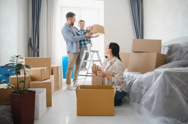 Mutlu aile taşınma günleri, aileler ve oğullar karton kutuları boşaltıp yeni evlerine yerleşiyorlar.