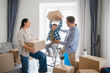 Aile taşınma gününden zevk alıyor, aileler ve çocuklar birlikte kutuları açıyor, yeni evlerinde mutlu anılar yaratıyorlar.