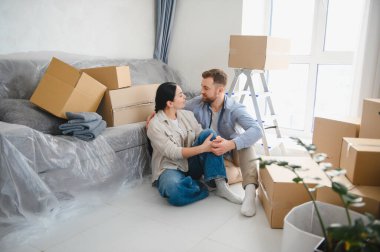 Karton kutularla çevrili yerde oturan mutlu çift yeni evlerini ve geleceklerini planlıyorlar.