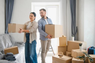 Karton kutular taşıyan genç bir çift yeni bir daireye ya da eve taşınıyor. Yeni başlangıçlar ve taşınma günü kavramı