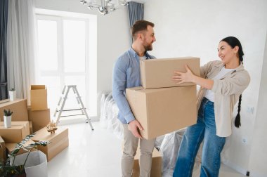 Yeni dairelerine taşınırken karton kutular taşıyan mutlu genç bir çift. Birlikte yaşamaya başlıyorlar.